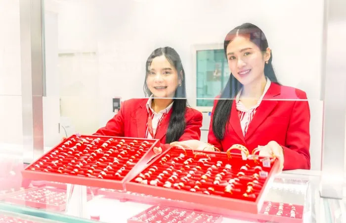 Two Money OK staff members holding jewellery trays behind the counter